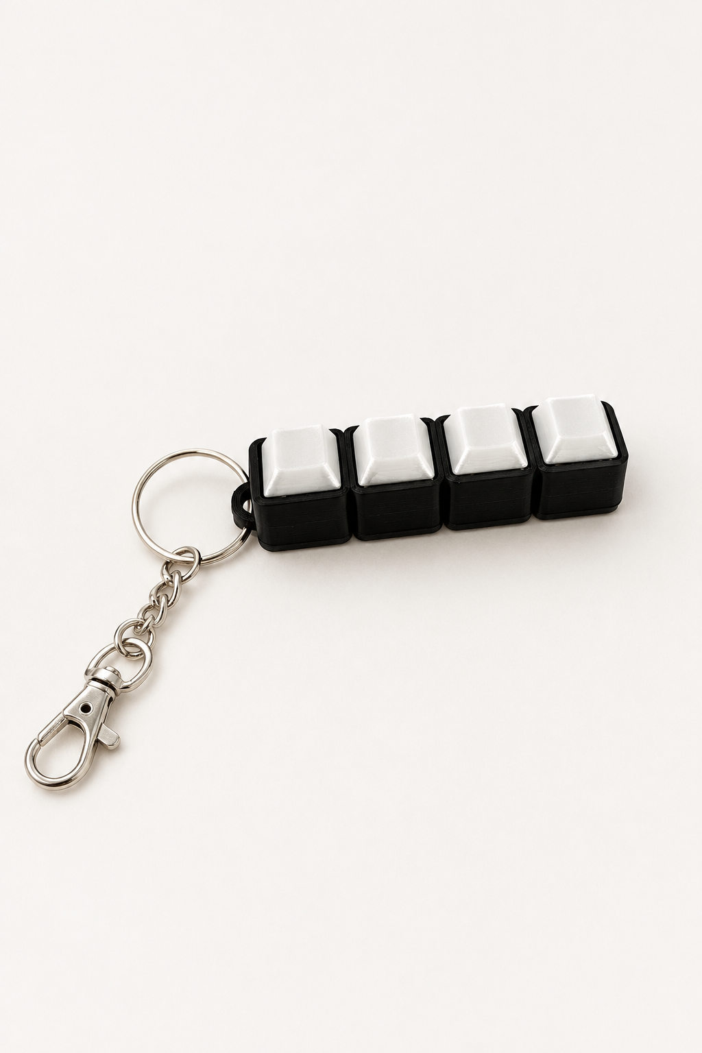 RE3D keyboard clicker with four white keys and a keychain